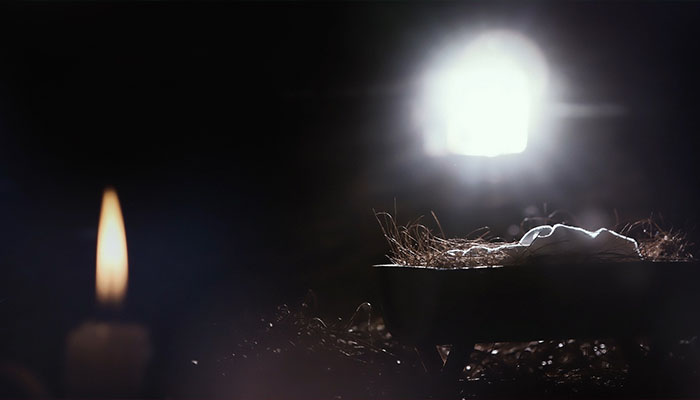 فوتیج کودک در یک آخور با نور روشن، شمع و شبستان