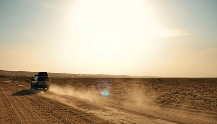 فوتیج حرکت ماشین نقره‌ای در مسیر صحرا و گرد و غبار