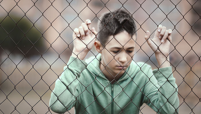 فوتیج پسر پناهنده تنها ایستاده است در نزدیکی حصار