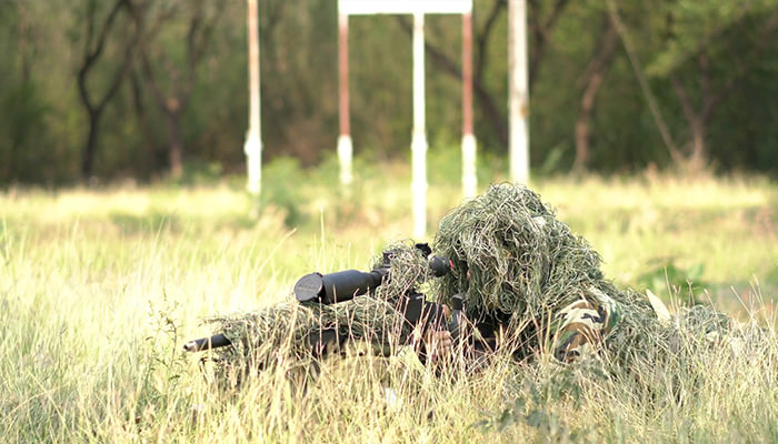 فوتیج سرباز تک تیرانداز دراز کشیده روی زمین و استتار در چمن
