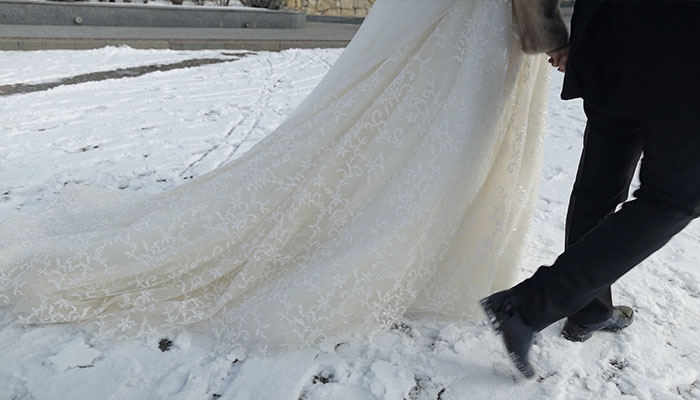 فوتیج تازه عروس و داماد با هم روی برف راه می روند