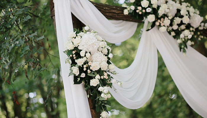 فوتیج طاق مراسم عروسی با گل های آویزان و فضای سبز با درختان و جنگل