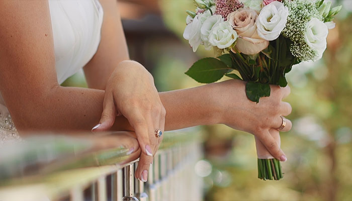 فوتیج عروس با دسته گل رز تازه به نرده بالکن تکیه داده است