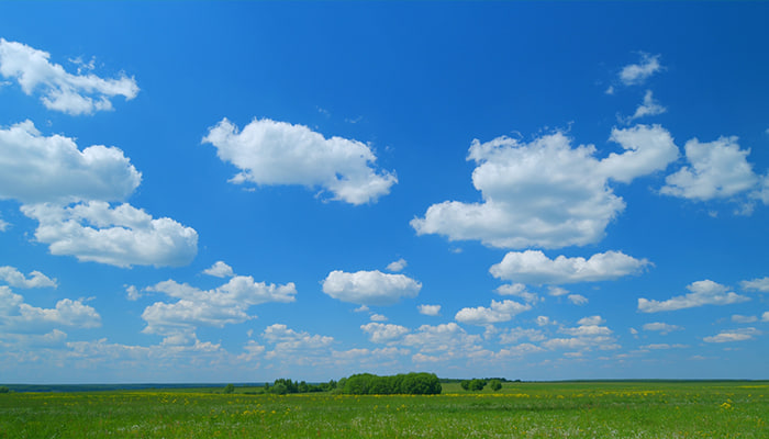 فوتیج منظره بهاری ابرها در آسمان آبی روشن بر فراز زمین سبز و درختان