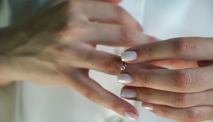 فوتیج زن جوان انگشتری طلا با الماس روی انگشت خود می گذارد